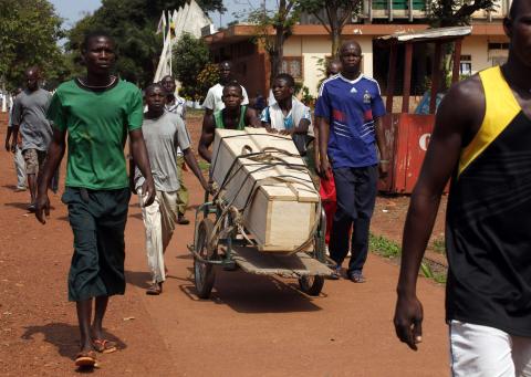 Men walk as they push a trolley loaded with a coffin in Bangui