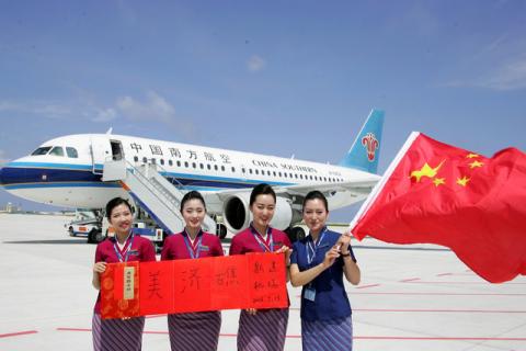 Crew members holding a Chinese national flag pose for pictures in front of a plane of the China Southern Airlines as the plane landed at a new airport China built on Mischief Reef of the Spratlys, South China Sea, July 13, 2016. PHOTO BY REUTERS/Stringer
