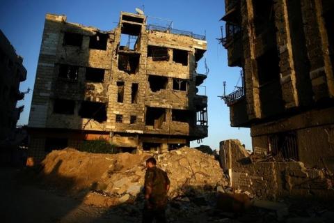 A fighter from the Free Syrian Army's Al Rahman legion walks past damaged buildings in the rebel held Jobar, a suburb of Damascus, Syria, September 6, 2016. PHOTO BY REUTERS/Bassam Khabieh