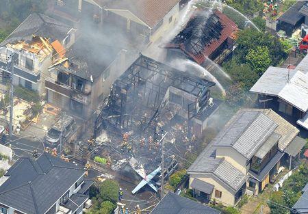 An aerial view shows debris of a crashed light plane (bottom C) and burning houses are seen after the plane went down in a residential area and burst into flames, in Chofu, outskirt of Tokyo, July 26, 2015. PHOTO BY REUTERS/Kyodo