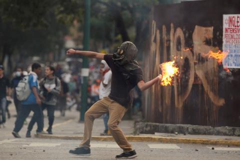 A demonstrator throws a molotov cocktail during clashes with riot police while rallying against Venezuela's President Nicolas Maduro in Caracas. PHOTO BY REUTERS/Christian Veron