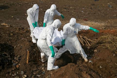 Health workers carry the body of a suspected Ebola victim for burial at a cemetery in Freetown, Sierra Leone, December 21, 2014. PHOTO BY REUTERS/Baz Ratner