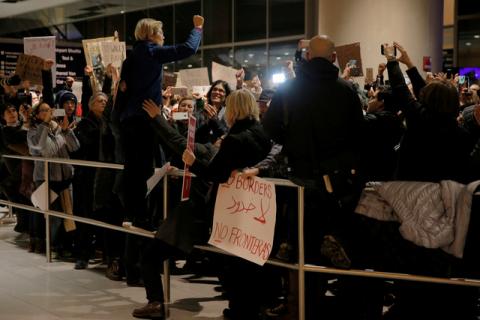 Senator Elizabeth Warren (D-MA) stands on a railing to address demonstrators protesting U.S. President Donald Trump's executive order travel ban at Logan Airport in Boston. PHOTO BY REUTERS/Brian Snyder