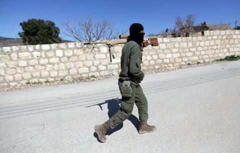 A Turkish-backed Free Syrian Army fighter holds a weapon as he walks north of Afrin, Syria, March 17, 2018. PHOTO BY REUTERS/Khalil Ashawi