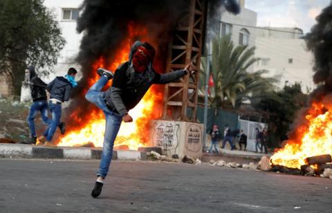 A Palestinian demonstrator hurls stones toward Israeli troops during clashes at a protest against U.S. President Donald Trump's decision to recognize Jerusalem as the capital of Israel, near the West Bank city of Nablus, December 29, 2017. PHOTO BY REUTERS/Mohamad Torokman