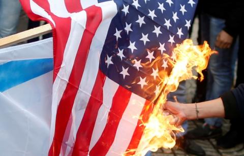 A Palestinian demonstrator burns a U.S. flag during a protest against the U.S. intention to move its embassy to Jerusalem and to recognize the city of Jerusalem as the capital of Israel, in Gaza City, December 6, 2017. PHOTO BY REUTERS/Mohammed Salem