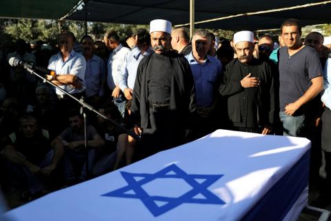 Members of the Druze community stand next to the flag-drapped coffin of Israeli Druze police officer Kamil Shanan during his funeral in the village of Hurfeish, Israel, July 14 2017. PHOTO BY REUTERS/Ammar Awad