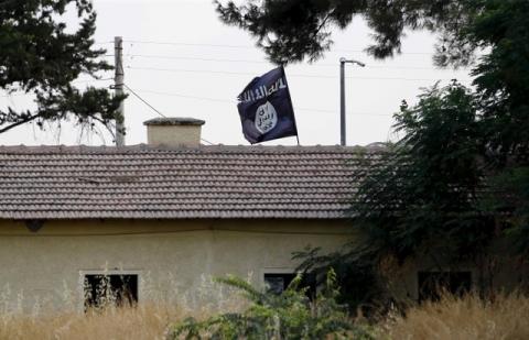 An Islamic State flag flies over the custom office of Syria's Jarablus border gate as it is pictured from the Turkish town of Karkamis, in Gaziantep province, Turkey August 1, 2015. PHOTO BY REUTERS/Murad Sezer