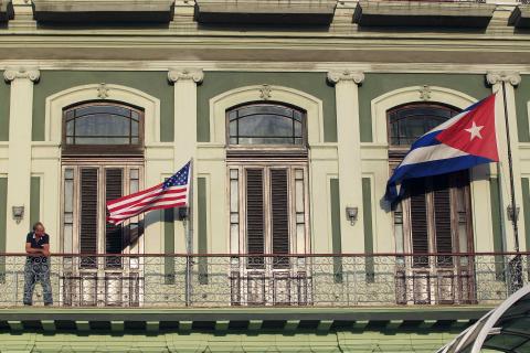 A man stands near the national flags of the U.S. and Cuba (R) on the balcony of a hotel being used by the first U.S. congressional delegation to Cuba since the change of policy announced by U.S. President Barack Obama on December 17, in Havana, January 19, 2015. PHOTO BY REUTERS/Stringer