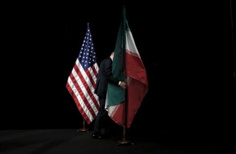 A staff member removes the Iranian flag from the stage during the Iran nuclear talks at the Vienna International Center in Vienna, Austria, July 14, 2015. PHOTO BY REUTERS/Carlos Barria