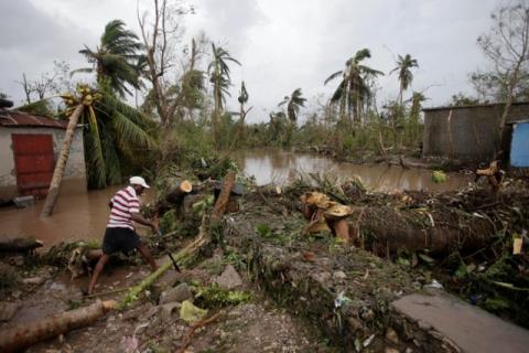 A man cuts branches off fallen trees in a flooded area by a river after Hurricane Matthew in Les Cayes, Haiti, October 5, 2016. PHOTO BY REUTERS/Andres Martinez Casares