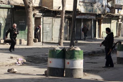A Free Syrian Army fighter guides a civilian (L) who is crossing a street, so as to avoid snipers from the Islamic State in Iraq and the Levant (ISIL), in the Kadi Askar neighbourhood of Aleppo