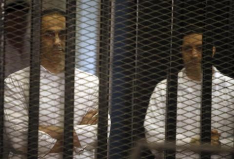 Gamal (L) and Alaa Mubarak, sons of former Egyptian President Hosni Mubarak, stand behind bars during their trial inside a dock at the police academy, on the outskirts of Cairo, June 8, 2013. PHOTO BY REUTERS/Amr Abdallah Dalsh