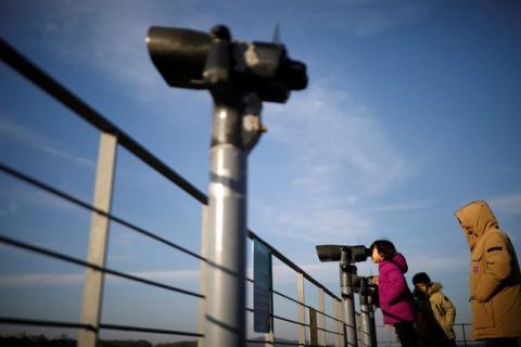A girl looks toward the North through a pair of binoculars near the demilitarized zone separating the two Koreas in Paju, South Korea, January 3, 2018. PHOTO BY REUTERS/Kim Hong-Ji