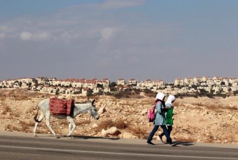 Palestinian schoolgirls walk with a donkey as the West Bank Jewish settlement of Maale Adumim, near Jerusalem, is seen in the background, November 13, 2013. PHOTO BY REUTERS/Ammar Awad