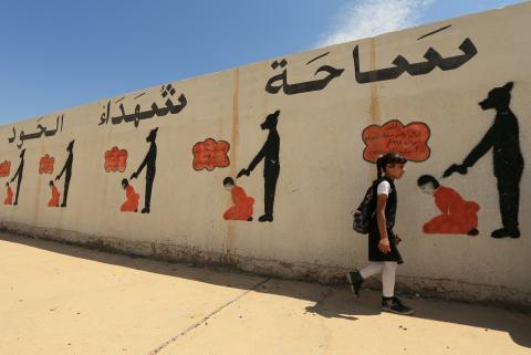 An Iraqi student walks past a school wall covered with drawings showing how Islamic State militants executed their prisoners in Mosul, Iraq, April 30, 2018. PHOTO BY REUTERS/Ari Jalal
