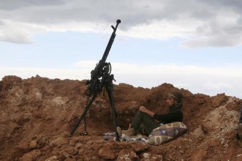 A rebel fighter sits near a weapon in Al-Lataminah village, northern Hama countryside, Syria, March 5, 2016. PHOTO BY REUTERS/Ammar Abdullah
