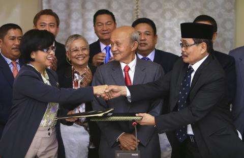Government of the Philippines (GPH) chief negotiator Miriam Coronel Ferer shake hands with Moro Islamic Liberation Front (MILF) chief negotiator Mohagher Iqbal (R) as they exchange peace agreements between both parties