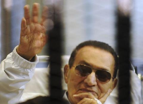Former Egyptian President Hosni Mubarak waves to his supporters inside a cage in a courtroom at the police academy in Cairo, April 13, 2013. PHOTO BY REUTERS/Stringer
