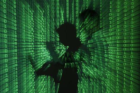 An illustration picture shows a projection of binary code on a man holding a laptop computer, in an office in Warsaw, June 24, 2013. PHOTO BY REUTERS/Kacper Pempel