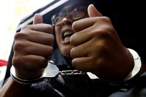 Detained Reuters journalist Wa Lone gestures to the media as he is escorted by police after a court hearing in Yangon, Myanmar, April 11, 2018. PHOTO BY REUTERS/Ann Wang