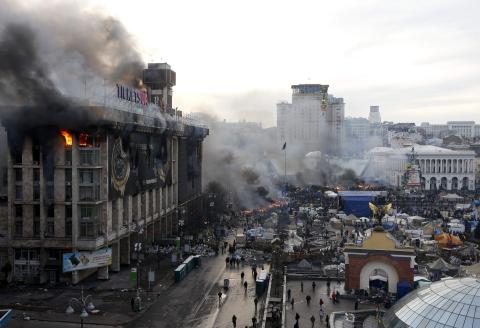 A trade union building is seen on fire in Independence Square as clashes between anti-government protesters with Interior Ministry members and riot police continue in central Kiev