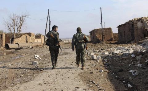 Members of the Kurdish People's Protection Units (YPG) walk past an area damaged by what activists said was a car blown up by a suicide bomber loyal to the Islamic State, in an attempt to target a YPG headquarter in Al-Hras village in Ras Al-Ain countryside, November 23, 2014. PHOTO BY REUTERS/Rodi Said