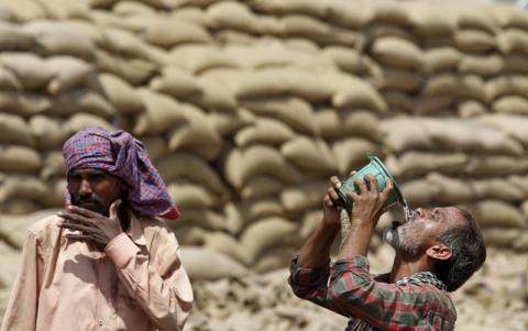 A labourer drinks water as another looks on, on a hot summer day at a grain market in Chandigarh, India April 19, 2016. PHOTO BY REUTERS/Ajay Verma