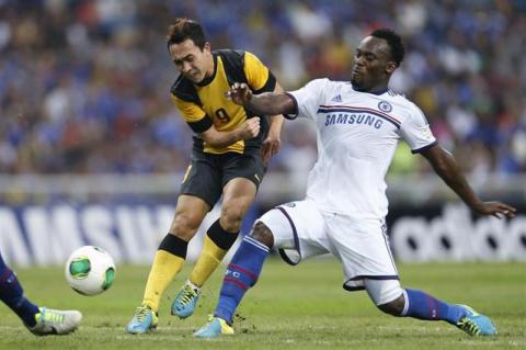 Malaysia's Norsharul Idlan Talaha (L) is challenged by Chelsea's Michael Essien during their friendly soccer match