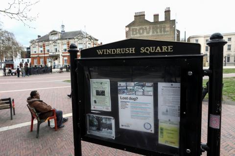 A man sits on a bench next to a sign on Windrush Square in the Brixton district of London, Britain, April 16, 2018. PHOTO BY REUTERS/Simon Dawson
