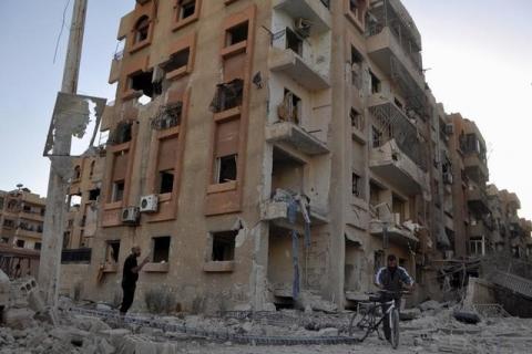 A man pushes a bicycle as another man stands on rubble at a site hit by what activists said were barrel bombs thrown by forces loyal to Syria's President Bashar Al-Assad, in the Palestinian Yarmouk refugee camp, southern outskirts of Damascus, June 3, 2015. PHOTO BY REUTERS/Moayad Zaghmout