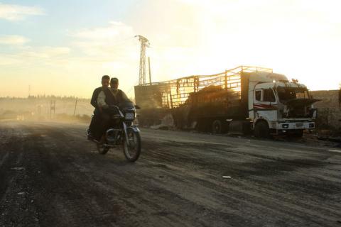 Men drive a motorcycle near a damaged aid truck after an airstrike on the rebel held Urm al-Kubra town, western Aleppo city, Syria, September 20, 2016. PHOTO BY REUTERS/Ammar Abdullah