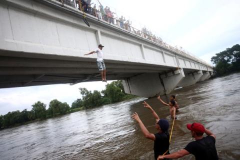 A Honduran migrant, part of a caravan trying to reach the U.S., jumps from the bridge that connects Mexico and Guatemala to avoid the border checkpoint in Ciudad Hidalgo, Mexico, October 19, 2018. PHOTO BY REUTERS/Edgard Garrido