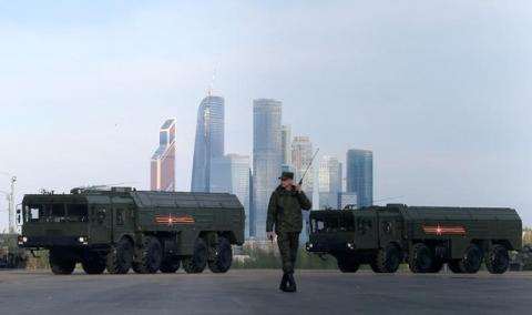 A Russian serviceman walks past Russian Iskander-M missile launchers before a rehearsal for the Victory Day parade, with the Moscow International Business Center also known as "Moskva-City" seen in the background, at a range in Moscow, Russia, May 5, 2016. PHOTO BY REUTERS/Maxim Shemetov