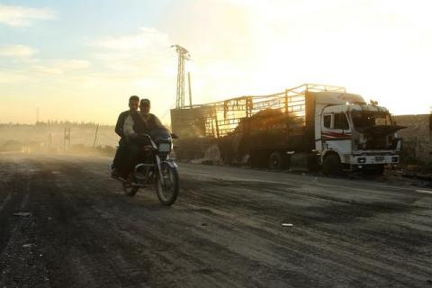 Men drive a motorcycle near a damaged aid truck after an airstrike on the rebel held Urm al-Kubra town, western Aleppo city, Syria, September 20, 2016. PHOTO BY REUTERS/Ammar Abdullah