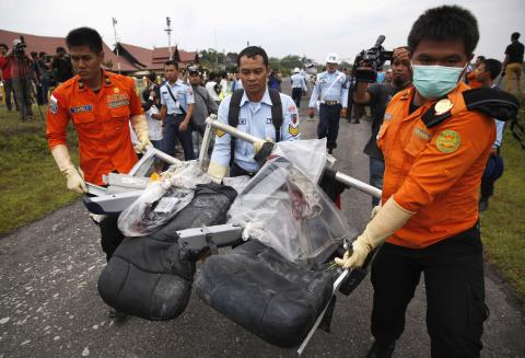 Parts of AirAsia QZ8501, recovered from the Java Sea, are carried by Indonesian Airforce and Search and Rescue crew members after they were offloaded from a U.S. Navy helicopter at the airport in Pangkalan Bun, Central Kalimantan January 5, 2015. REUTERS/Darren Whiteside