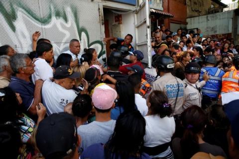People gather to try to buy pasta while riot police try to control the crowd outside a supermarket in Caracas, Venezuela, June 10, 2016. PHOTO BY REUTERS/Carlos Garcia Rawlins
