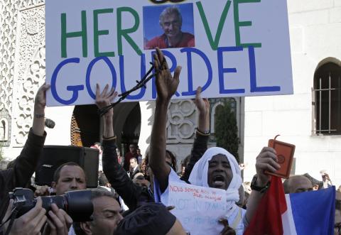 A man holds a placard which reads "Homage to Herve Gourdel", a French mountain guide who was beheaded by an Algerian Islamist group, during a gathering of Muslims in front of the Paris Mosque after Friday prayers
