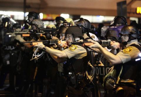 Police officers point their weapons at demonstrators protesting against the shooting death of Michael Brown in Ferguson, Missouri