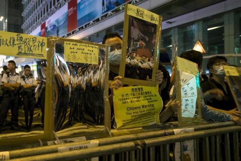 Police officers are reflected on reflective materials held by a pro-democracy protesters on a blocked road at Mongkok shopping district in Hong Kong October 19, 2014. PHOTO BY REUTERS/Tyrone Siu