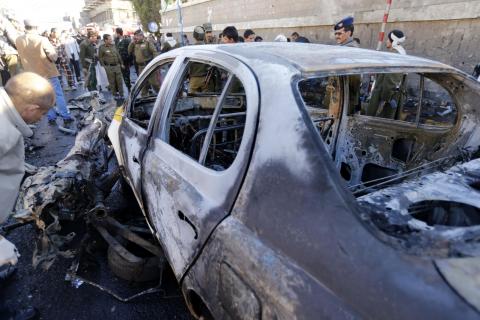 A police investigator looks at a damaged car at the scene of a car bomb outside the police college in Sanaa, January 7, 2015. PHOTO BY REUTERS/Khaled Abdullah