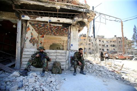 Members of Syrian police sit at a damaged building at the city of Douma, Damascus, Syria, April 16, 2018. PHOTO BY REUTERS/Ali Hashisho