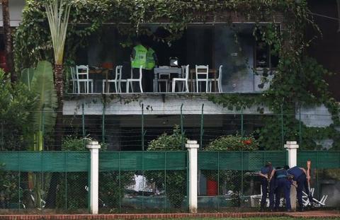 Policemen sneak a look inside the Holey Artisan Bakery and the O'Kitchen Restaurant as others inspect the site after gunmen attacked, in Dhaka, Bangladesh, July 3, 2016. PHOTO BY REUTERS/Adnan Abidi
