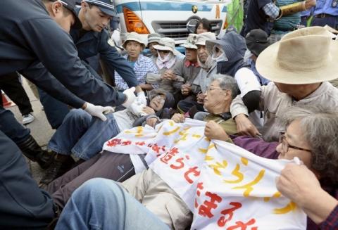 Protesters lie on the ground as they try to block work on a contentious U.S. air base in front of the gate of the U.S. Marine Corps Camp Schwab in Nago on the southern Japanese island of Okinawa, in this photo taken by Kyodo, October 29, 2015. PHOTO BY REUTERS/Kyodo