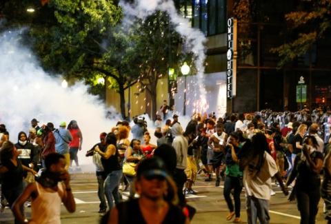 People run from flash-bang grenades in uptown Charlotte, NC during a protest of the police shooting of Keith Scott, in Charlotte, North Carolina, U.S., September 21, 2016. PHOTO BY REUTERS/Jason Miczek