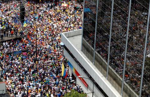 People participating in an opposition rally are reflected in the glass windows of a building in Caracas, Venezuela, April 8, 2017. PHOTO BY REUTERS/Christian Veron