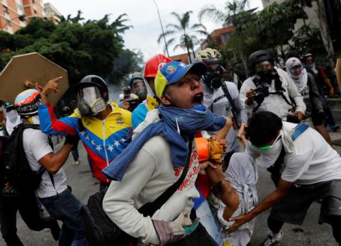 An injured opposition supporter is helped by others while clashing with riot police during a rally against President Nicolas Maduro in Caracas, Venezuela, May 3, 2017. PHOTO BY REUTERS/Carlos Garcia Rawlins