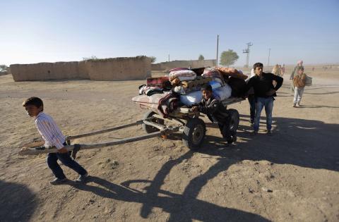 Kurdish Syrian refugees carry their belongings after crossing the Turkish-Syrian border, near the southeastern town of Suruc in Sanliurfa province