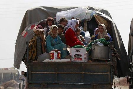 Civilians fleeing the recent fightings in their area sit at the back of a pickup truck with their belongings in the southern countryside of Aleppo, Syria, October 21, 2015. PHOTO BY REUTERS/Hosam Katan