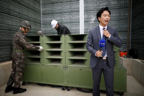 A reporter prepare a news report as South Korean soldiers dismantle loudspeakers that were set up for propaganda broadcasts near the demilitarized zone separating the two Koreas in Paju, South Korea, May 1, 2018. PHOTO BY REUTERS/Kim Hong-Ji
